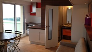 Een moderne keuken met een eethoek, een bank en een schuifdeur naar een balkon.