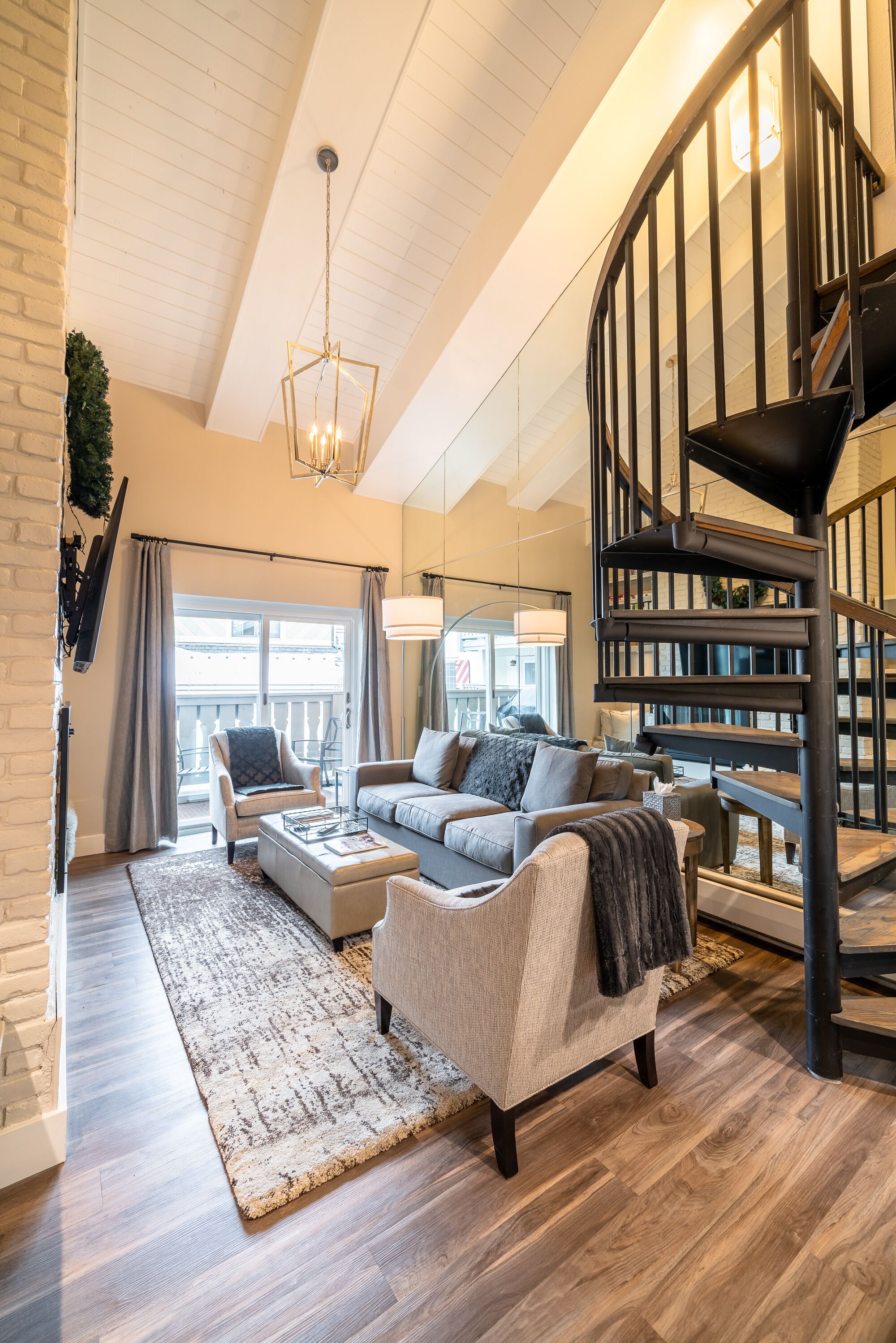Open living room with vaulted ceiling, gas fireplace, and balcony access 