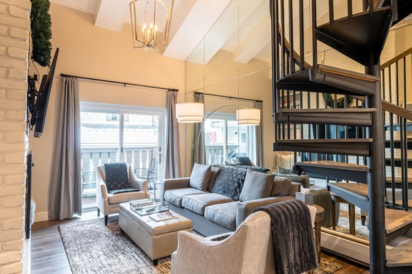 Open living room with vaulted ceiling, gas fireplace, and balcony access