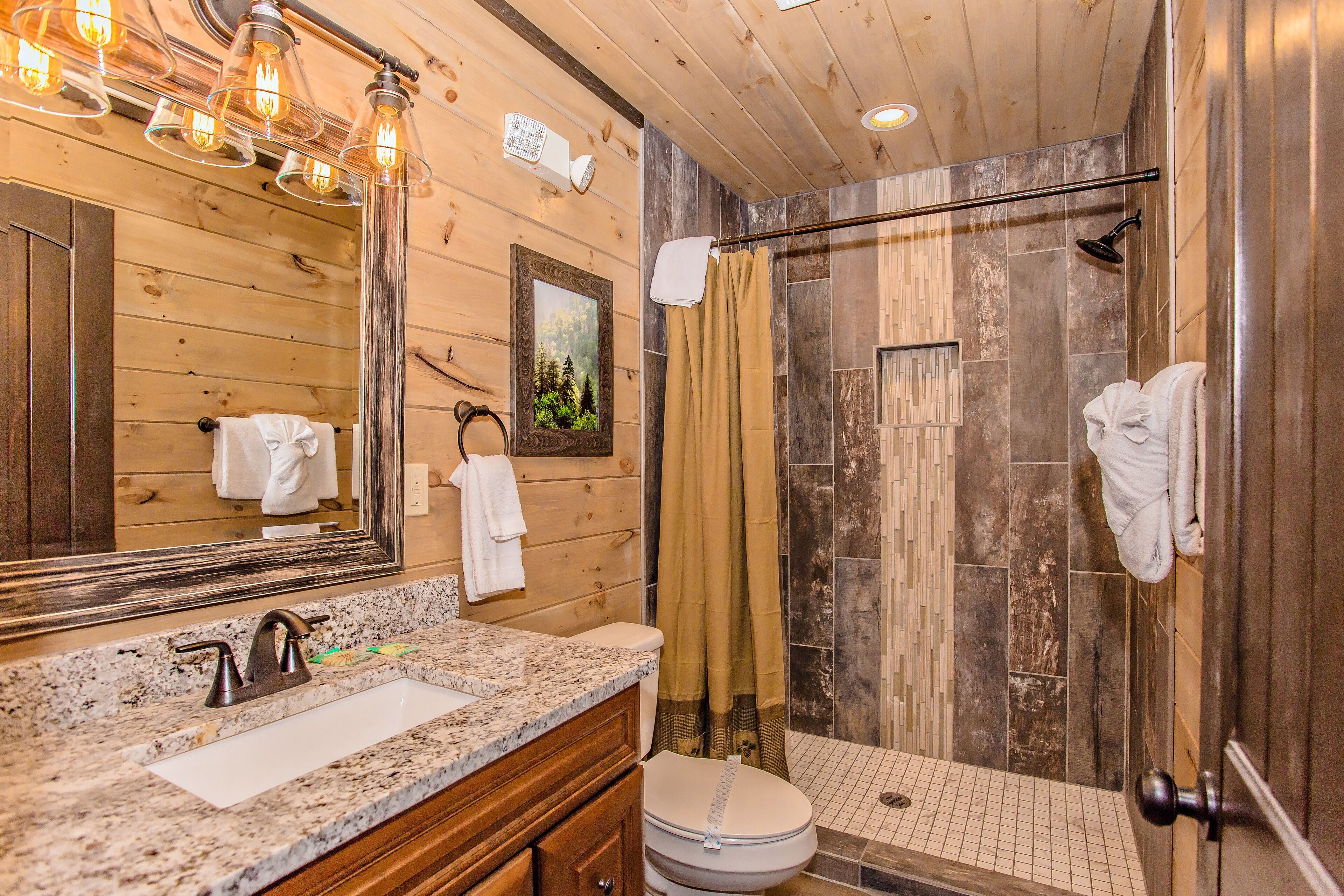 A bathroom with a wooden vanity, a sink, a toilet, and a shower area with a glass door.