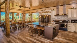 Une cuisine spacieuse dotée d’un grand îlot central, de planchers en bois et offrant une vue sur l’extérieur.