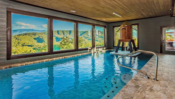 Une piscine intérieure dotée de grandes fenêtres offrant une vue panoramique sur les montagnes.