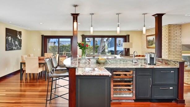 A spacious kitchen with a marble countertop, dark cabinetry, and pendant lighting.