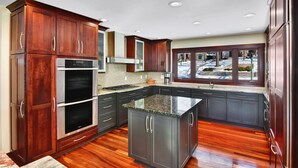 A modern kitchen with dark wood cabinets, stainless steel appliances, and a large island.