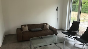 A modern living room with a brown sofa, a glass coffee table, and two black chairs. - Kruft-apps (Kruft)