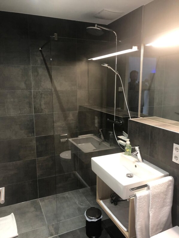 A modern bathroom with a glass-enclosed shower, a white sink, and a mirror above the sink.