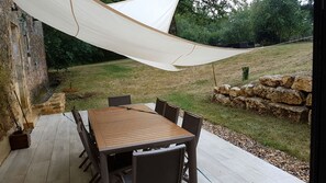 Um deck de madeira com mesa e cadeiras, cercado por um toldo branco.