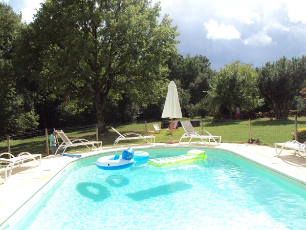 Piscina com espreguiçadeiras e um flutuador.