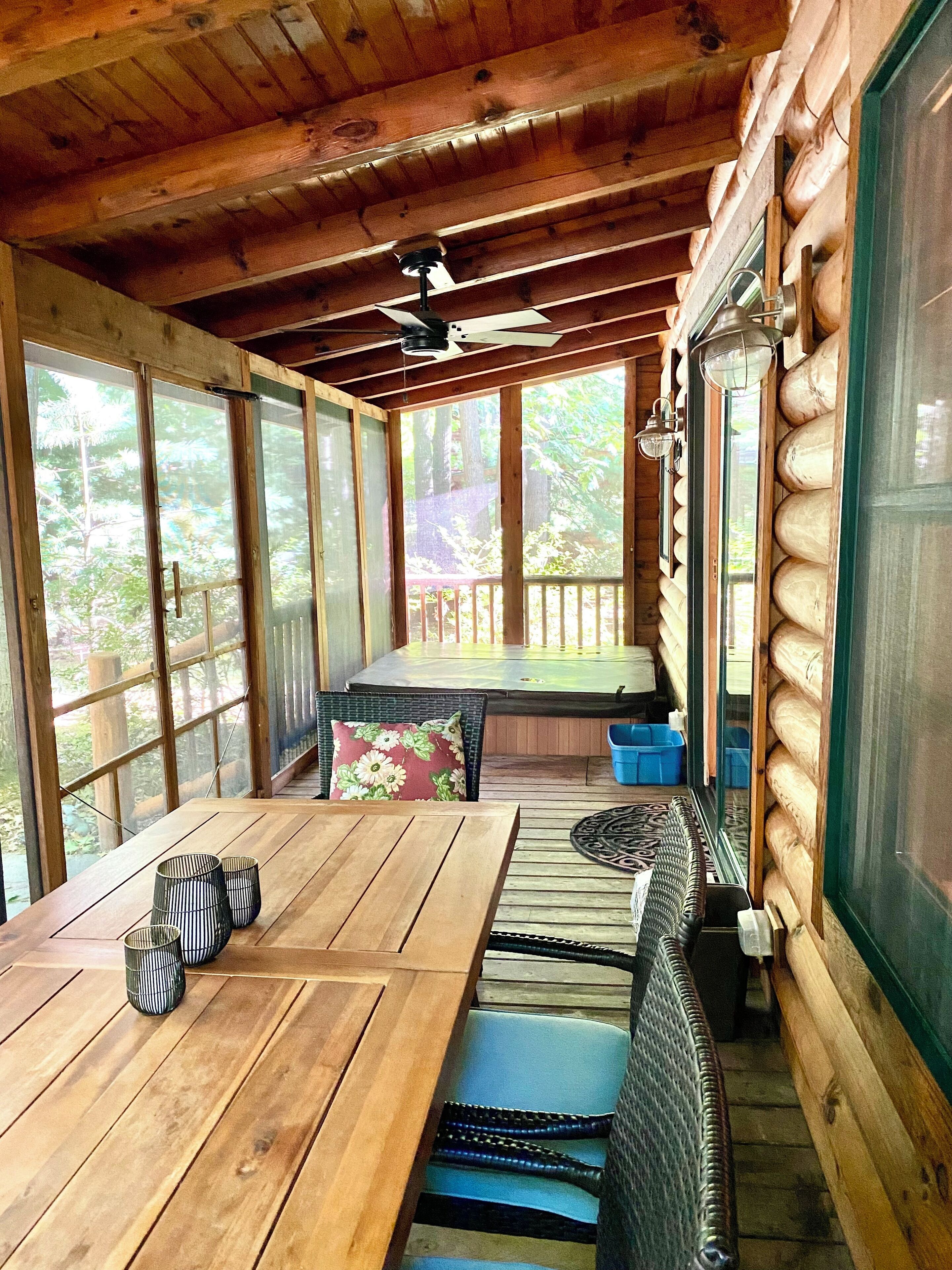 A wooden cabin with a large dining table, benches, and a ceiling fan.