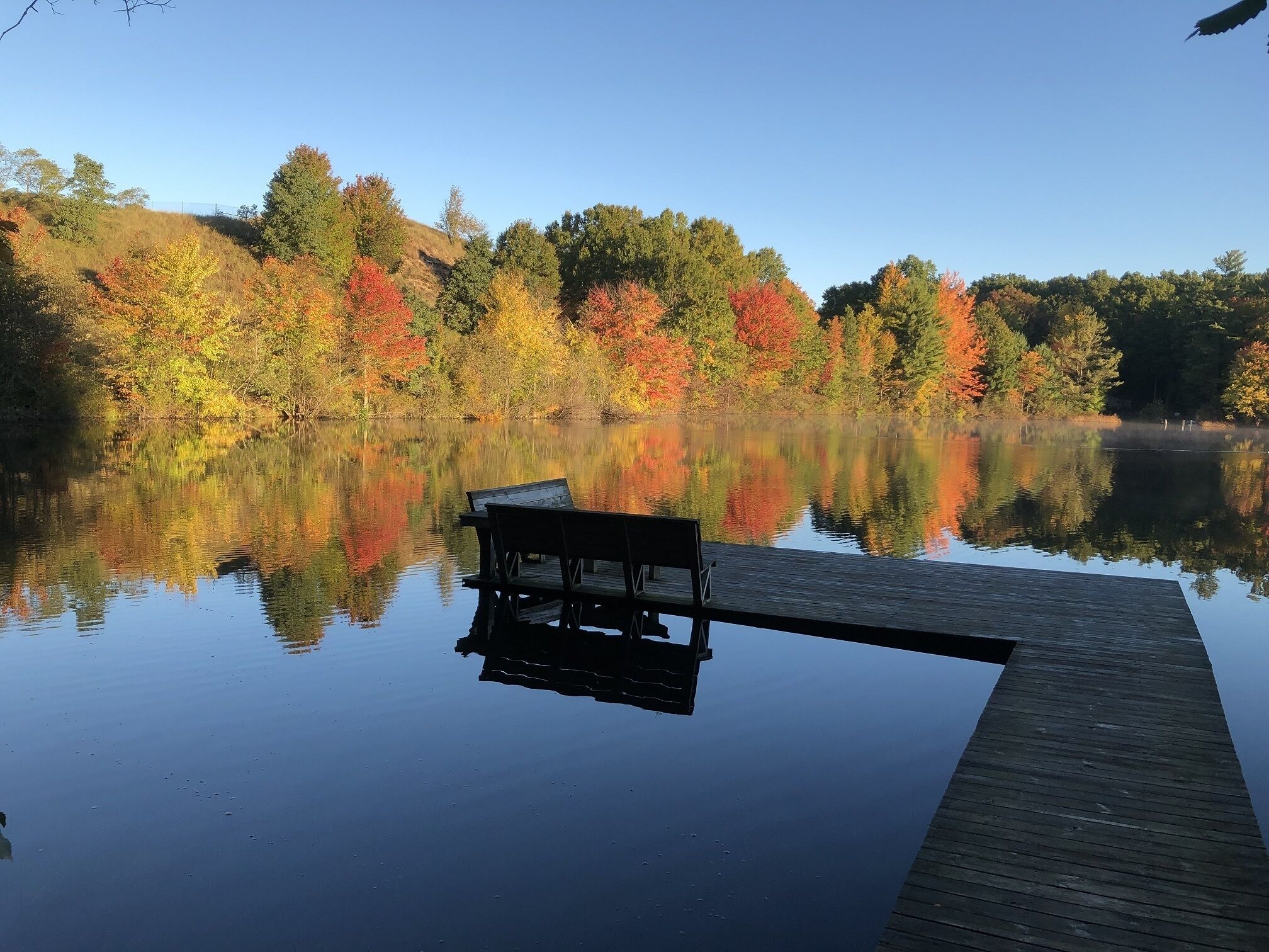 Un lac paisible avec une jetée en bois et un banc.