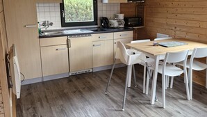 Una cocina moderna con armarios de madera, un ventanal grande y una zona de comedor con sillas blancas.
