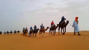 Un grupo de personas montando camellos a través de un paisaje desértico.
