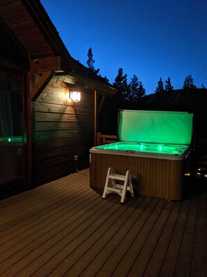 Un bain à remous doté d’une terrasse en bois et d’une échelle, entouré d’une structure de cabane en bois.