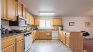 Una cocina con armarios de madera, microondas, estufa y lavavajillas.