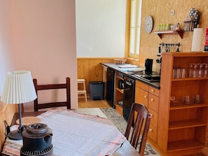 A kitchen with wooden cabinets, a stove, a sink, and a dining table with chairs.