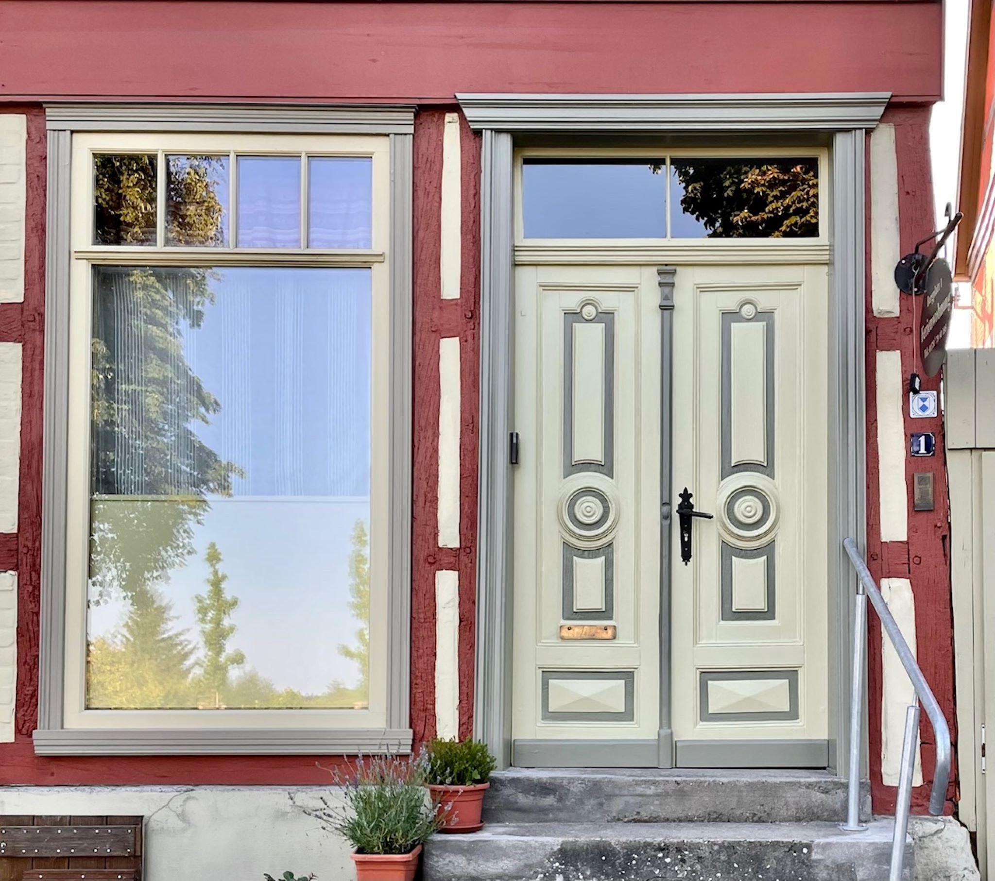 Un bâtiment à deux étages, doté d’une façade rouge et blanche, d’un ensemble de portes doubles avec un trou de serrure, et d’une petite marche menant à l’entrée.