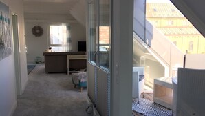 Un intérieur moderne avec une porte vitrée donnant sur un balcon, des planchers recouverts de moquette et une cuisine ouverte.