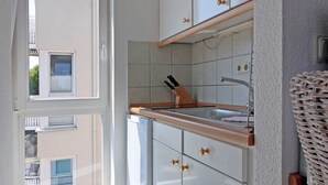 Kompakti keittiö, jossa on valkoiset kaapit, ruostumattomasta teräksestä valmistettu pesuallas ja puinen työtaso.