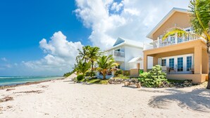 Una propiedad frente a la playa con una casa grande, un balcón y vista al océano.