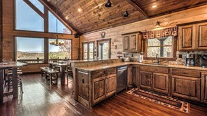 A rustic kitchen with wooden cabinets, a large island, and a view of the outdoors.