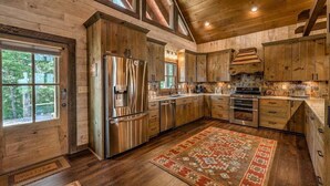 Une cuisine spacieuse dotée de meubles en bois, d’appareils électroménagers en acier inoxydable et d’un grand tapis.