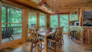 A wooden cabin with a dining area, kitchen, and large windows. - Southern Comfort- Lake Front | 2 Level Dock | Paved Roads and Driveway (Morganton)