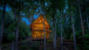 A two-story wooden cabin with a balcony, surrounded by trees. - Southern Comfort- Lake Front | 2 Level Dock | Paved Roads and Driveway (Morganton)