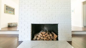 Una chimenea de ladrillo blanco con una pila de leña.