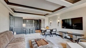 A modern living room with a sofa, ottoman, and a coffee table. There is a dining area with a table and chairs, and a kitchen in the background. - SPECIAL! Ritz-Carlton Bachelor Gulch 2BR&2BA Residence INSIDE hotel adj to Lift! (Avon)