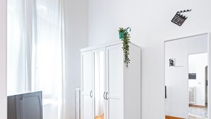 A room with a white wardrobe, a glass table with a laptop and remote, a potted plant, and a mirror on the wall. - Very central - Via Po Torino (Torino)