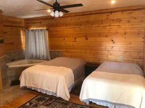 Une cabine équipée de deux lits, d’un ventilateur de plafond et d’une baignoire.