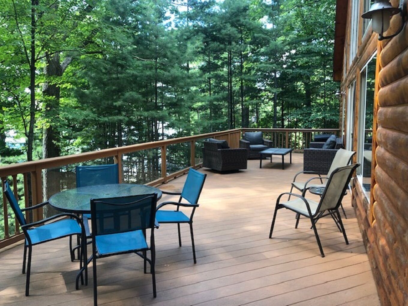 A covered deck with outdoor furniture, surrounded by trees.