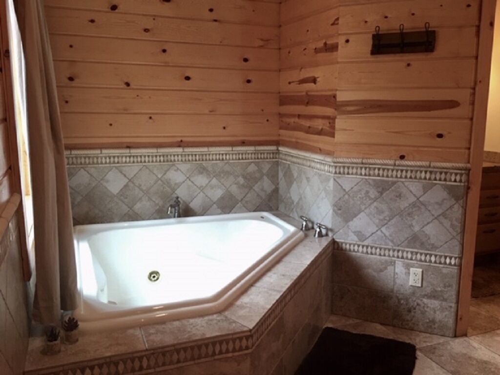 A bathroom with a freestanding bathtub, tiled walls, and wooden paneling.