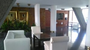 A modern lobby with white sofas, a glass table, and a reception desk. - Lindo apartamento a una cuadra de la Playa Brava. (Punta del Este)