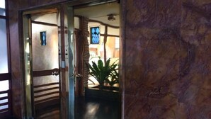 A hotel entrance with a glass door, a potted plant inside, and a view of the interior. - Lindo apartamento a una cuadra de la Playa Brava. (Punta del Este)