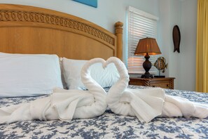 Un lit bien fait, avec une couvre-lit à motifs floraux, une tête de lit en bois, une lampe de chevet et une décoration murale représentant des poissons.