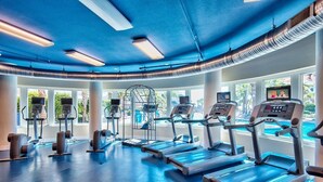 Un gimnasio con cintas de correr, elípticas y un amplio ventanal con vistas al exterior.