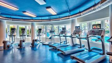 Un gimnasio con cintas de correr, elípticas y un amplio ventanal con vistas al exterior.