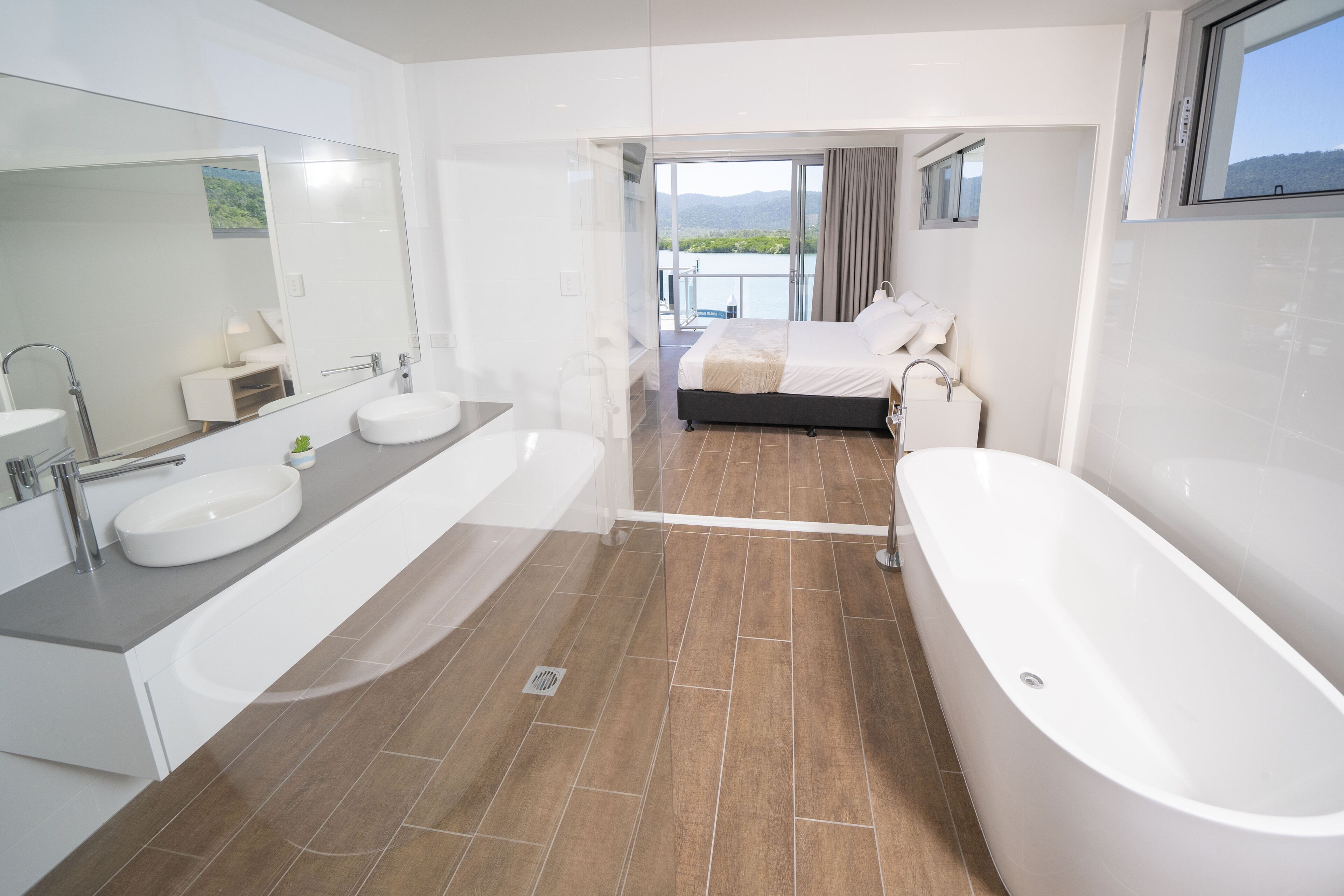 Een moderne badkamer met een ruim bad, een dubbele wastafel en een grote spiegel.