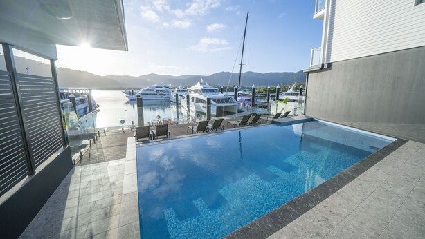 A swimming pool with a view of boats and mountains. - Harbour Cove (Airlie Beach)