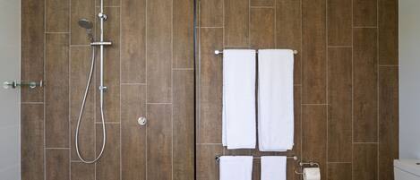 A bathroom with wooden walls, a shower, and two white towels hanging on hooks.