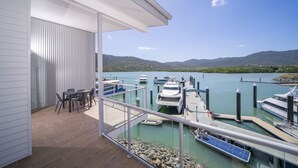 A balcony with a view of a marina, boats, and a mountainous landscape. - Harbour Cove (Airlie Beach)