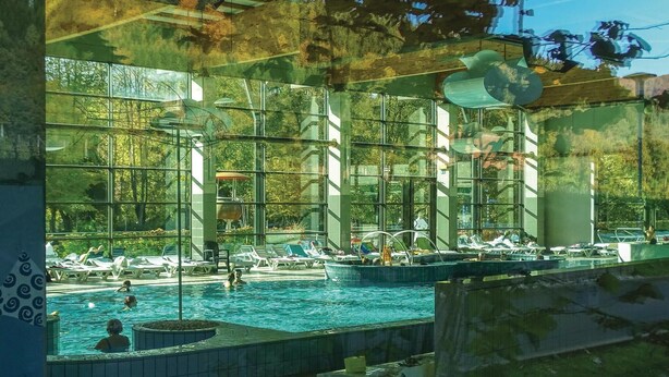 A swimming pool with clear glass walls, surrounded by lounge chairs and a few people swimming. - Amazing home in Kostel with WiFi (Kostel)