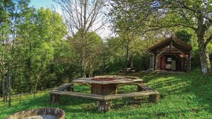 A rustic wooden structure with a small porch and a picnic table in a lush green forest setting. - Amazing home in Kostel with WiFi (Kostel)