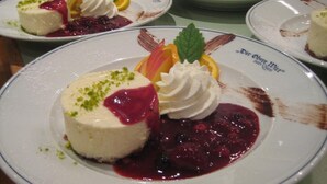 A dessert plate with a cheesecake, whipped cream, and berry sauce, garnished with mint leaves. - Der Obere Wirt zum Queri (Andechs)