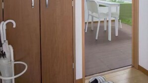 A room with a wooden wardrobe, a white chair, a small table, and a welcome sign on the wall. - Not Ninja Osaka Namba 1 (Osaka)