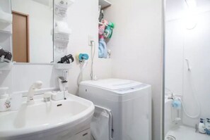 A bathroom with a sink, toilet, and shower. There are toiletries on the wall and a towel rack. - Not Ninja Osaka Namba 1 (Osaka)