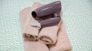 A folded beige towel with a Panasonic hairdryer on top, placed on a patterned surface. - Not Ninja Osaka Namba 1 (Osaka)