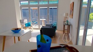 A modern living room with a dining table, a sofa, and a glass door leading to an outdoor area.