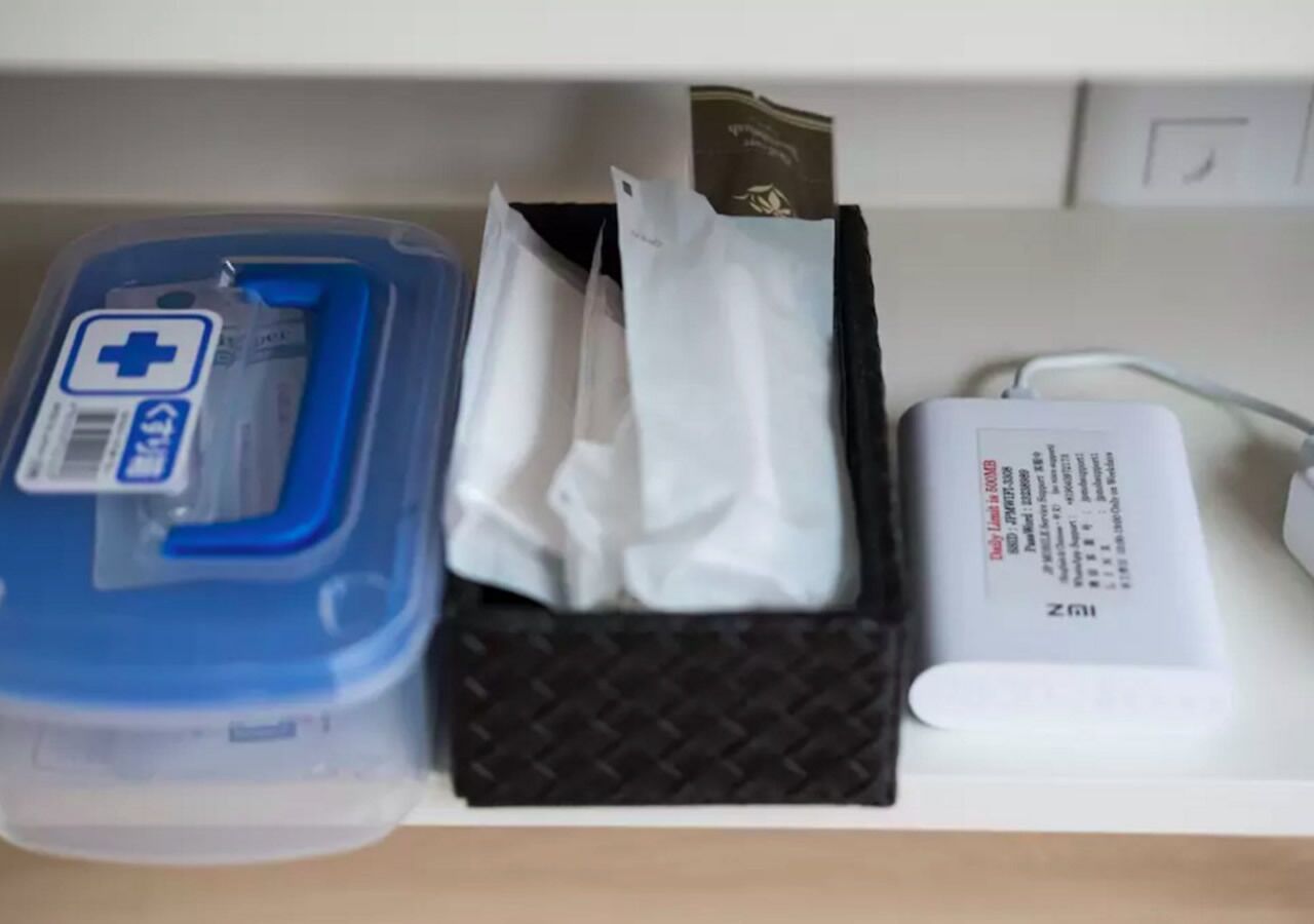 A shelf with a blue container with a medical symbol, a black box with tissue, and a white device with a cable.
